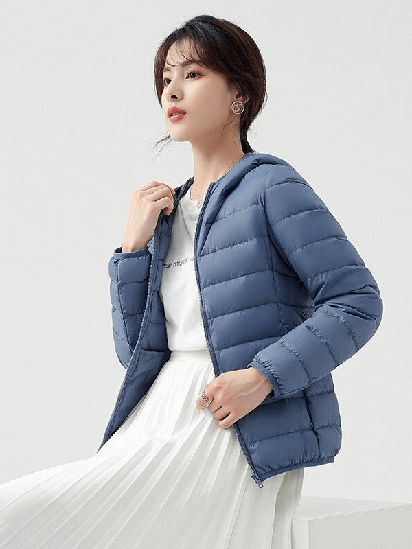Woman wearing a stylish blue women's down jacket with hood, featuring windproof and waterproof design, perfect for outdoor activities.